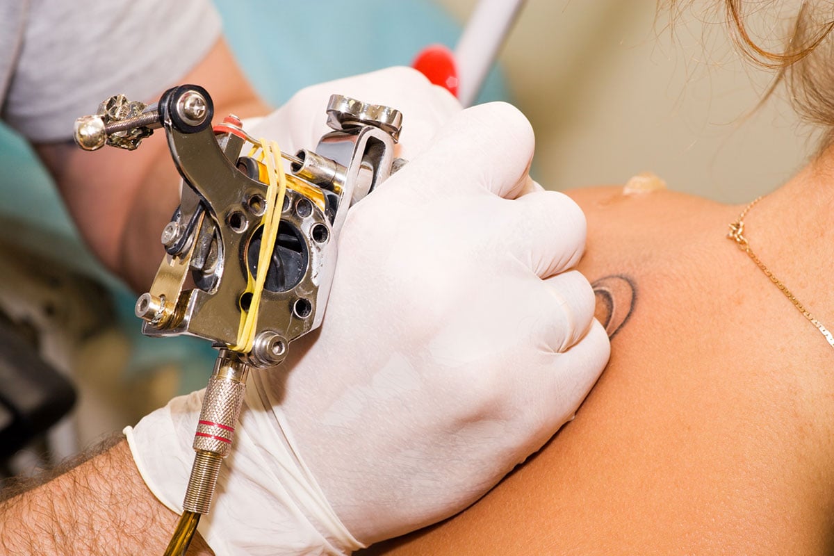 Woman getting tattoo on back.